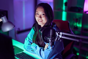 Poster - Young chinese woman streamer smiling confident sitting with arms crossed gesture at gaming room