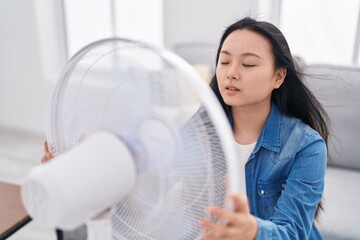 Sticker - Young chinese woman using ventilator sitting on sofa at home