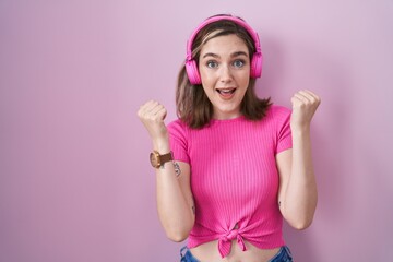 Poster - Blonde caucasian woman listening to music using headphones screaming proud, celebrating victory and success very excited with raised arms