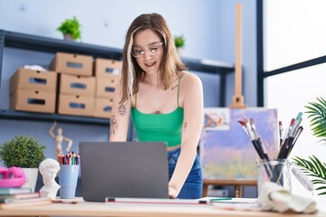 Sticker - Young woman artist using laptop sitting on table at art studio