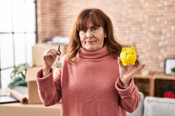 Sticker - Middle age hispanic woman holding piggy bank and house keys skeptic and nervous, frowning upset because of problem. negative person.