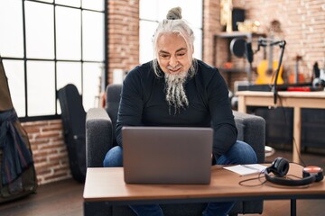 Sticker - Middle age grey-haired man musician using laptop sitting on chair at music studio