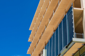 Glass curtain wall being installed on an engineered timber multi story green, sustainable, residential high rise apartment building construction project