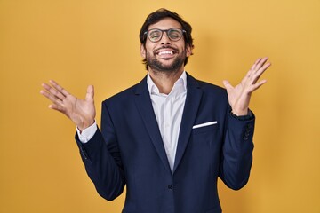 Wall Mural - Handsome latin man standing over yellow background celebrating crazy and amazed for success with arms raised and open eyes screaming excited. winner concept