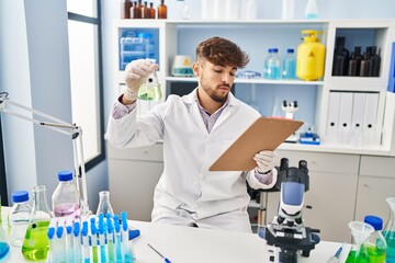 Canvas Print - Young arab man scientist measuring liquid reading report at laboratory