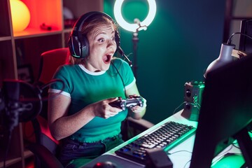 Poster - Young redhead woman streamer playing video game using joystick at gaming room