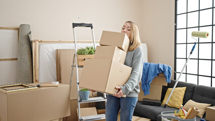 Canvas Print - Young blonde woman holding packages at new home