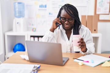 Canvas Print - African american woman business worker talking on smartphone drinking coffee at office