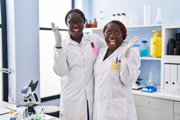 Poster - Two african women working at scientist laboratory celebrating victory with happy smile and winner expression with raised hands