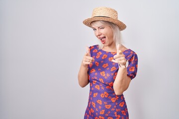 Poster - Young caucasian woman wearing flowers dress and summer hat pointing fingers to camera with happy and funny face. good energy and vibes.