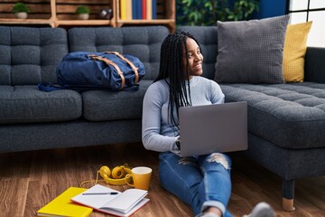 Poster - African american woman student sitting on floor using laptop at street