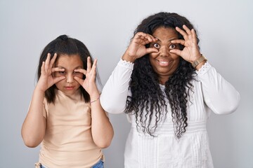 Sticker - Mother and young daughter standing over white background trying to open eyes with fingers, sleepy and tired for morning fatigue