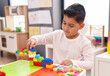 © Krakenimages.com - Adorable hispanic boy playing with construction blocks sitting on table at kindergarten