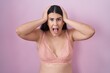 Young hispanic woman wearing pink bra crazy and scared with hands on head, afraid and surprised of shock with open mouth