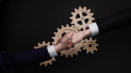 Two businessmen shaking hands on a black background. The concept of a joint solution