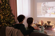 Couple watching romantic Christmas movie via video projector at home