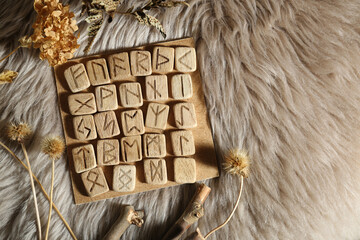 Wall Mural - Many wooden runes and dried flowers on fur, flat lay. Space for text