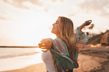 Portrait of one young woman at the beach with openened arms enjoying free time and freedom outdoors. Having fun relaxing and living happy moments..