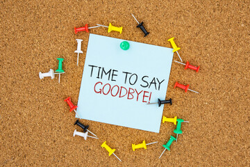 Poster - Time to say goodbye text on light blue post-it paper pinned on bulletin cork board surrounding by multi color pins. This message can be used in business concept about farewell.