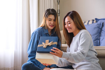 Wall Mural - A young couple women opening a gift box together