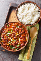 Wall Mural - Rajma masala is a Indian vegetarian dish consisting of red kidney beans in a thick gravy with many spices served with rice close-up on a wooden tray on the table. Vertical top view from above