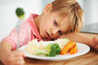 Sad, healthy and a child with vegetables for dinner, unhappy and problem with food. Frustrated, hungry and a little boy eating broccoli and carrots, disappointed with lunch and nutrition for youth