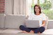 © Alexandra W/peopleimages.com - Portrait, laptop and woman on a home sofa with a smile while streaming online. Happy female person relax on couch for remote work while studying research or email with internet connection in a lounge