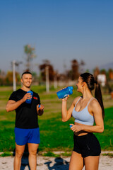 Wall Mural - Fitness couple is about to drink some water while having a conversation