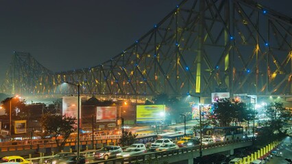 Wall Mural - Timelapse view of traffic exiting architectural landmark Howrah Bridge illuminated at night in Kolkata, West Bengal, India, zoom in. 