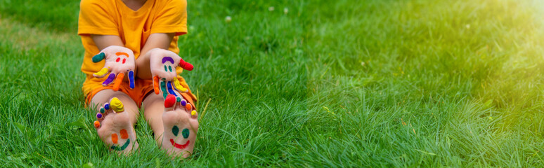 Wall Mural - Children's hands in the colors of summer, a smile on the boy's palm.