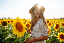 Beautiful Woman Posing In A Field Of Sunflowers In A Dress And Hat.  Fashion, Lifestyle, Travel And Vacations Concept.