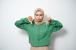 © rizkitripujiw - Sad young Asian Muslim woman dressed in casual showing thumbs down
