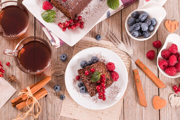 Wall Mural - Chocolate sponge cake with fresh fruit on white dish.