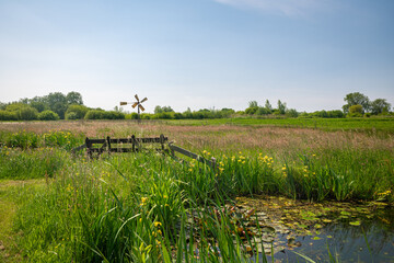 Wall Mural - idyllic view of a fence and small windmill in the dutch polder landscape near gouda, holland