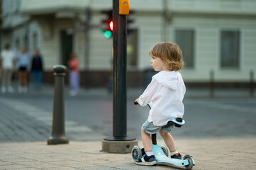 Canvas Print - Funny toddler boy riding a baby scooter outdoors on summer day. Kid training balance on mini bike. Summer activities for kids.