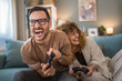 © Miljan Živković - couple man and woman husband wife play console video games at home