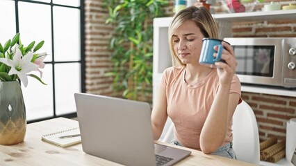 Poster - Young blonde woman using laptop drinking coffee at dinning room