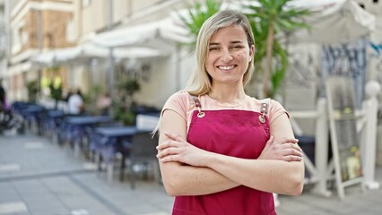 Poster - Young blonde woman waitress smiling confident standing with arms crossed gesture at coffee shop terrace