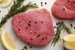Raw tuna fillets with peppercorns, lemon and rosemary on white table, flat lay