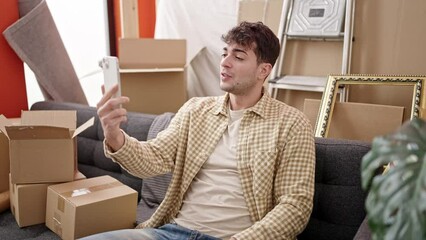 Canvas Print - Young hispanic man doing video call sitting on the sofa at new home