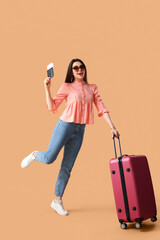 Canvas Print - Young woman with passport and suitcase on beige background