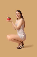 Poster - Beautiful young woman with tasty birthday cake on beige background