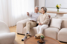Cheerful Senior Couple Watching TV At Home