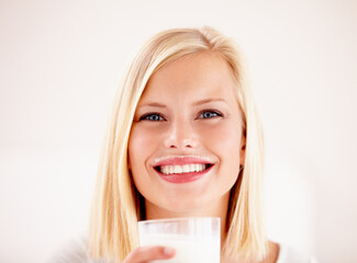 Wall Mural - Portrait, milk mustache and a woman drinking from a glass in studio isolated on a white background. Happy, nutrition and calcium with a health young female enjoying a drink for vitamins or minerals