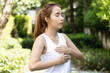 Young asian woman practicing qigong or reiki meditation for internal health and self healing in green urban park