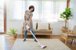 Portrait of young woman housewife hands holding mop cleaning floor with smart object technology in modern living room. Daily routine cleaning. Domestic housework service concept