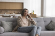 © fizkes - Happy middle aged woman making telephone call from home, talking on mobile phone, enjoying leisure, cellphone conversation, communication, resting on sofa, smiling, laughing