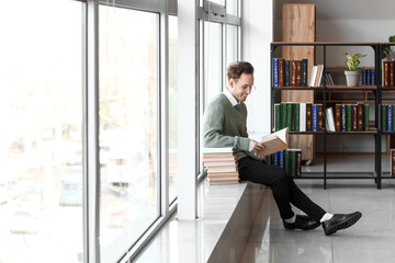 Wall Mural - Young man reading book in library