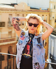 Tattoo, portrait and woman with sunglasses in city, urban body art or stylish fashion outdoor. Face, rooftop or trendy female person from Canada in cool denim clothes, jacket or serious punk attitude