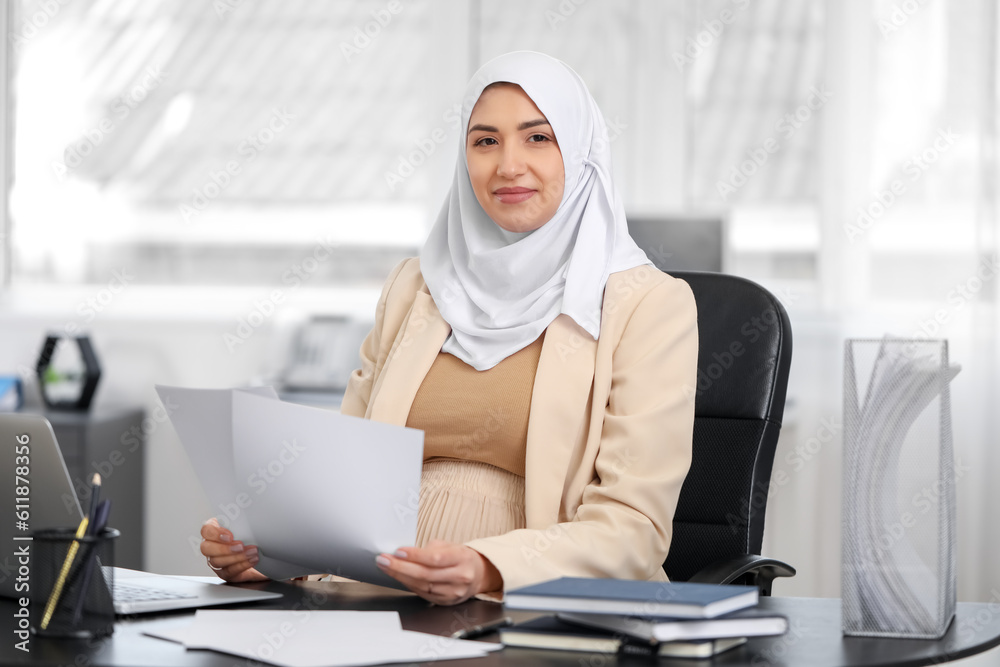 Young pregnant Muslim woman working with documents at table in office